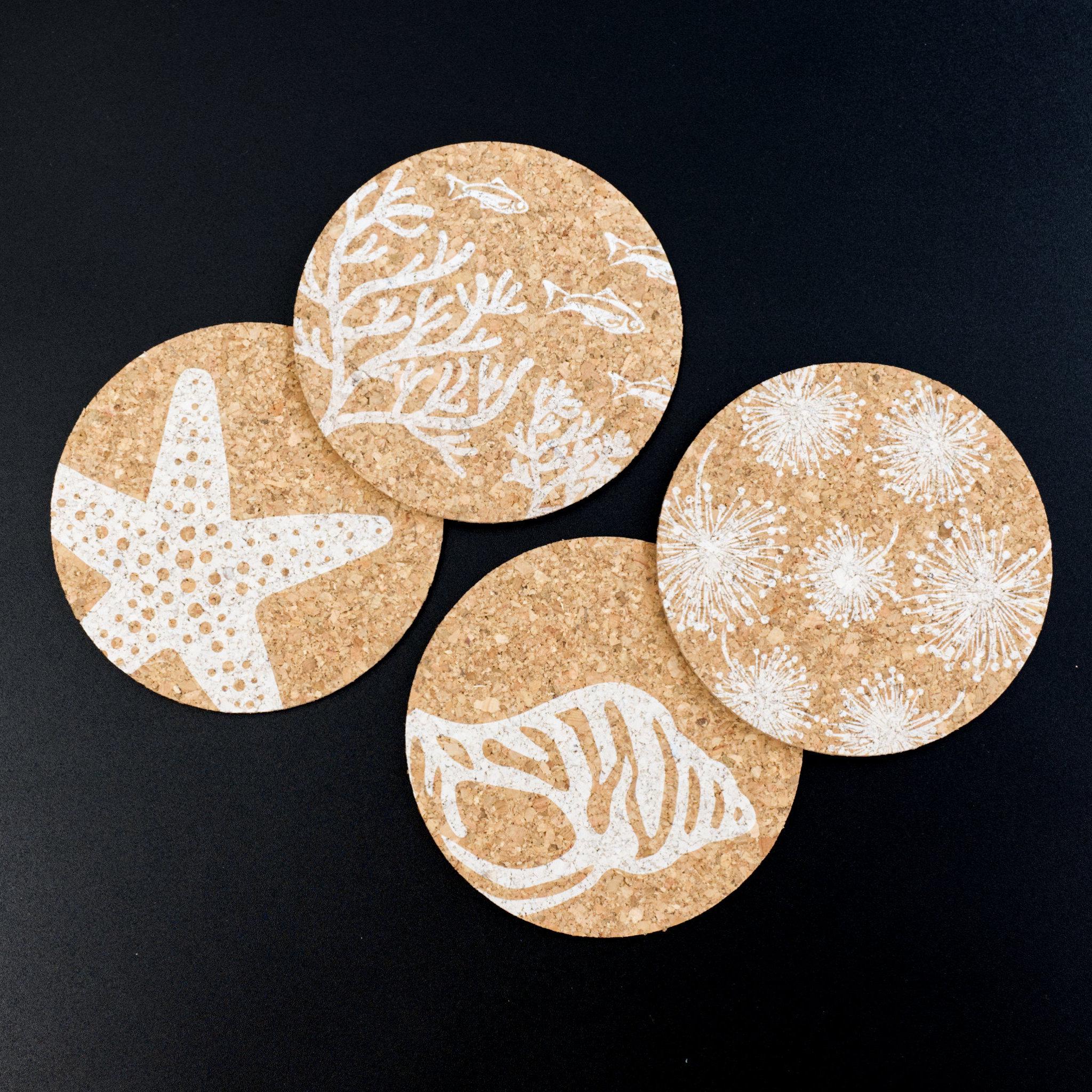 four home by the sea cork coasters with different marine patterns from Hem And Tassel on black background