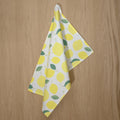rich cotton percale kitchen towel of Amalfi Lemon design hanging against wooden backdrop - from Hem And Tassel