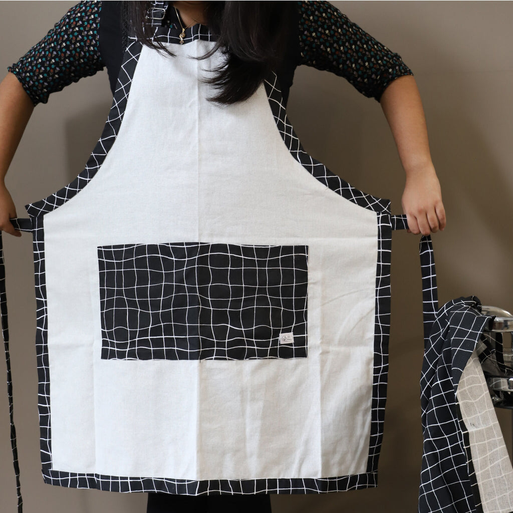 Person holding a white apron with black pocket and wavy patterns on pocket
