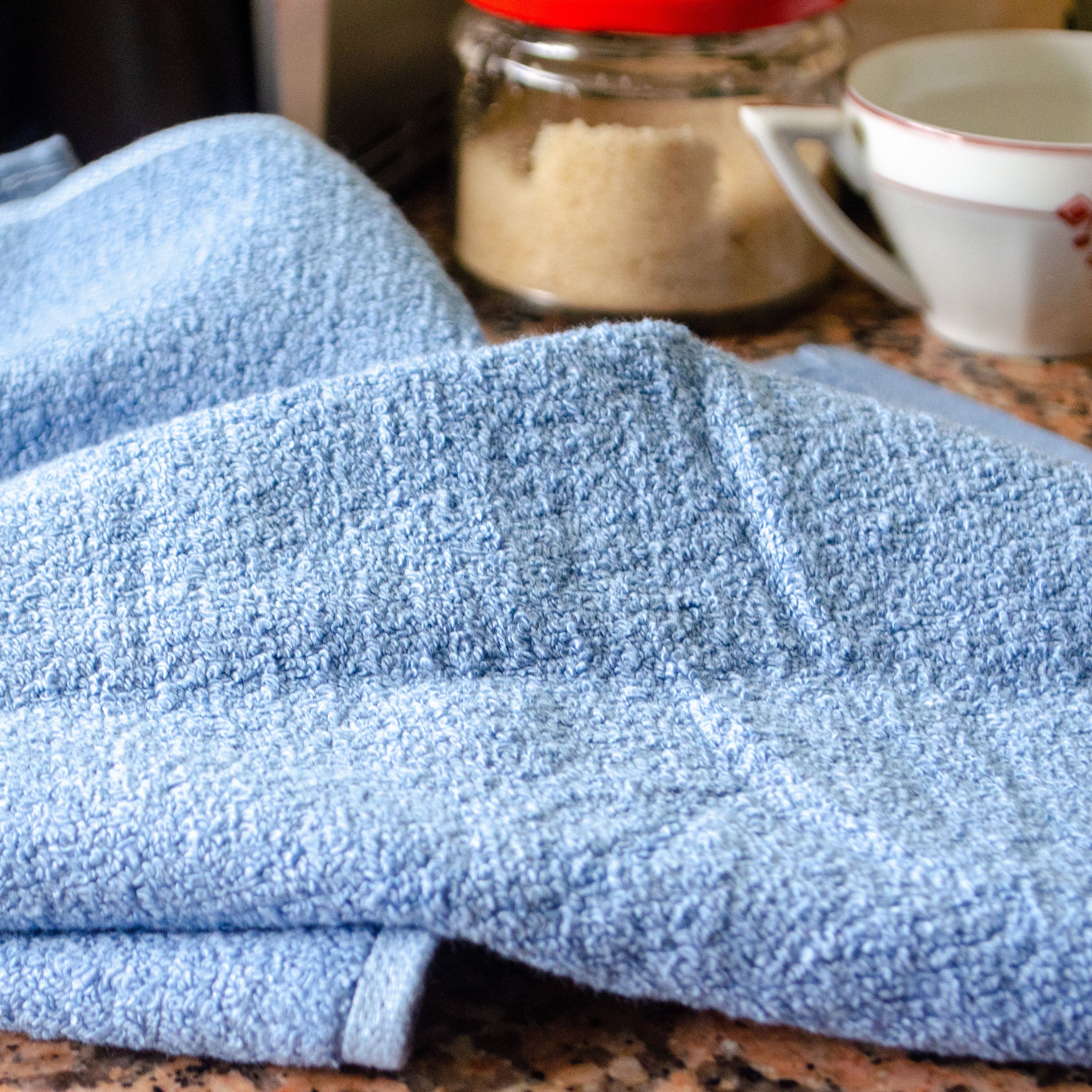 Blue Jekyll and Hyde towel on a kitchen counter with a jar and cup in the background