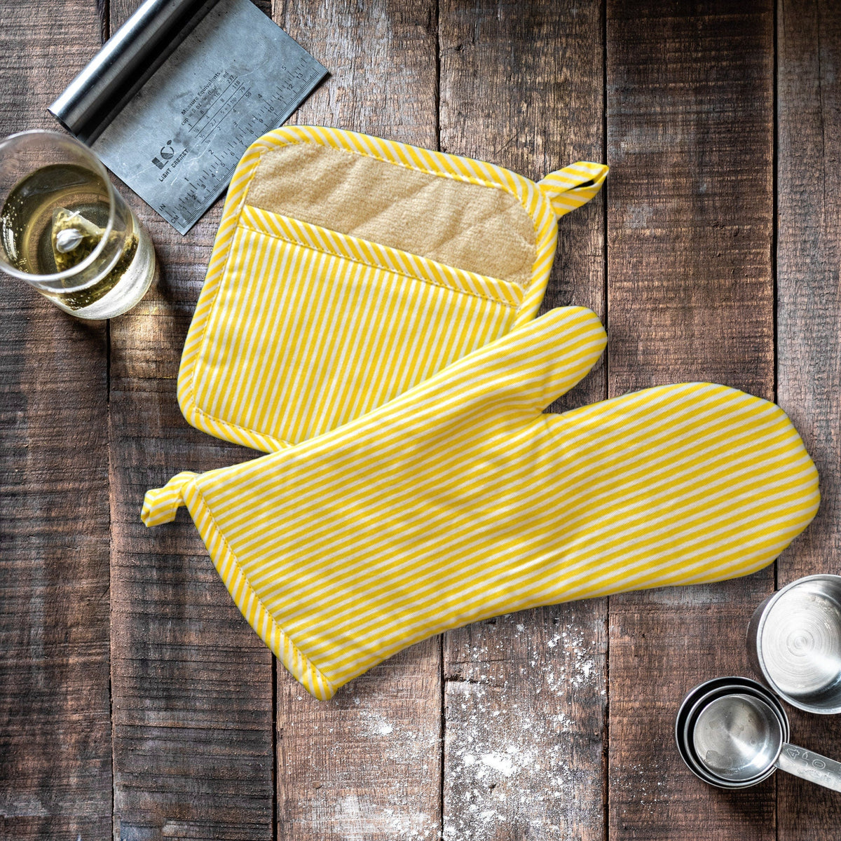 banker stripes deign oven mitt and pot holder in yellow butter cup on a wooden kitchen table - from Hem And Tassel