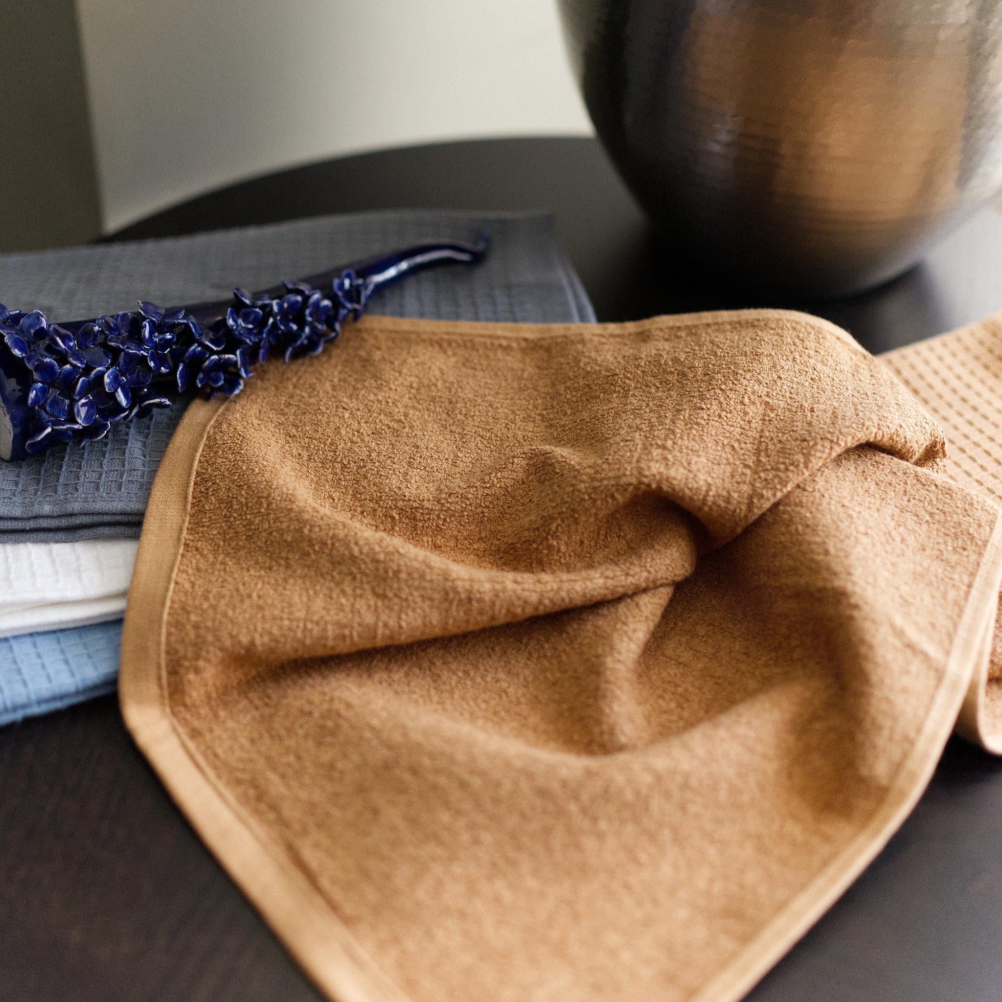 Camel Jekyll and Hyde towel close up on a dark surface with a blurred background and other three colors of towels shown folded