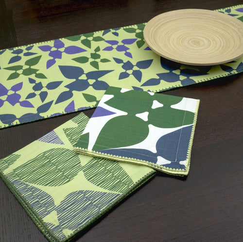 Green and blue patterned desert haze table runner on a dark surface from hem and tassel