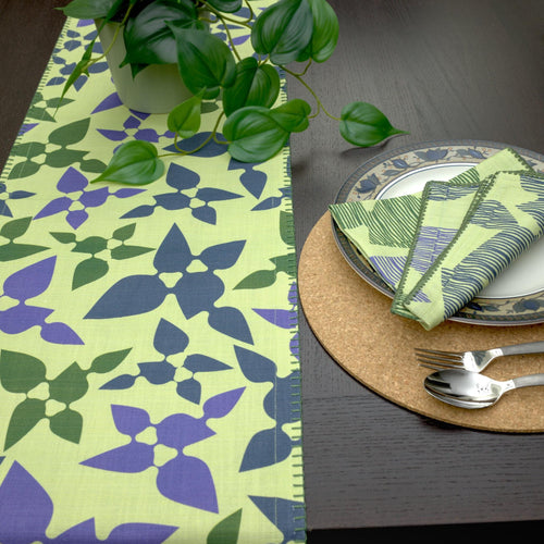 textured slub-cotton table runner with decorative edging, in celebration design, with matching turf dinner napkins and place setting on wooden dining table - from Hem And Tassel