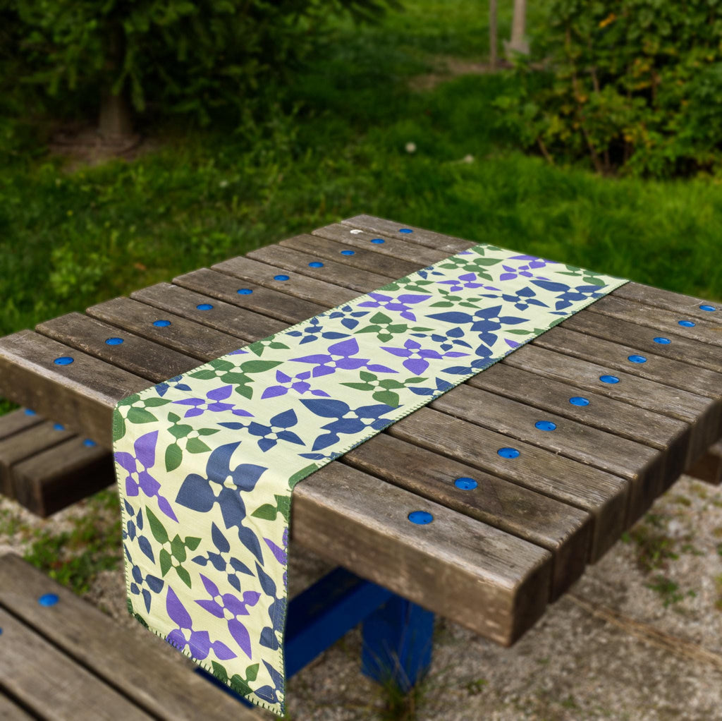 Floral-patterned Celebration table runner on a wooden table outdoors from hem and tassel