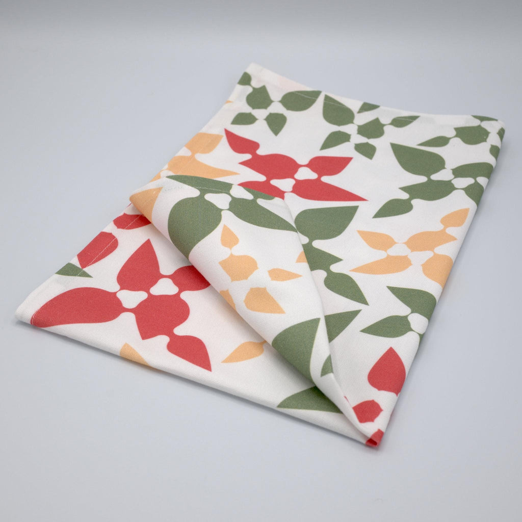 Celebration tea towel folded with floral patterns on a gray background from Hem And Tassel 