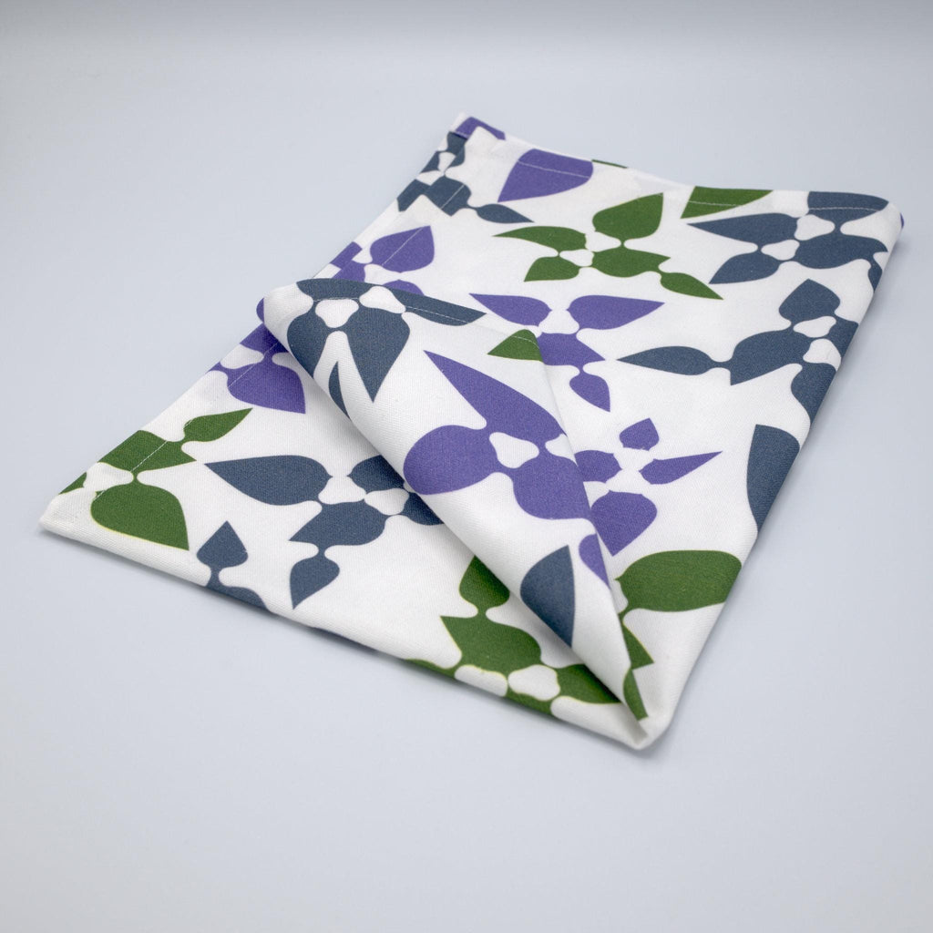 Celebration tea towel folded with leaf pattern on a gray background from Hem And Tassel 