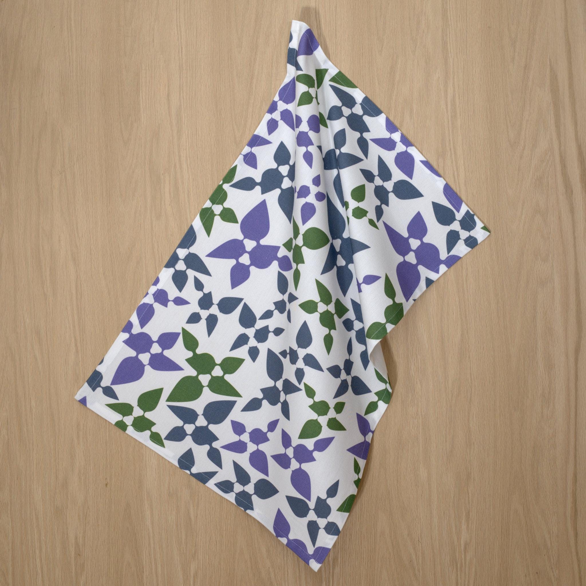 rich cotton percale kitchen towel of 'celebration' design in purple, hanging on light wood backdrop - from Hem And Tassel