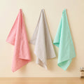 ultra fine weave - set of three 100% cotton kitchen towels in soft pastel shades of pink, grey and foam, hanging against a cream backdrop, from Hem And Tassel
