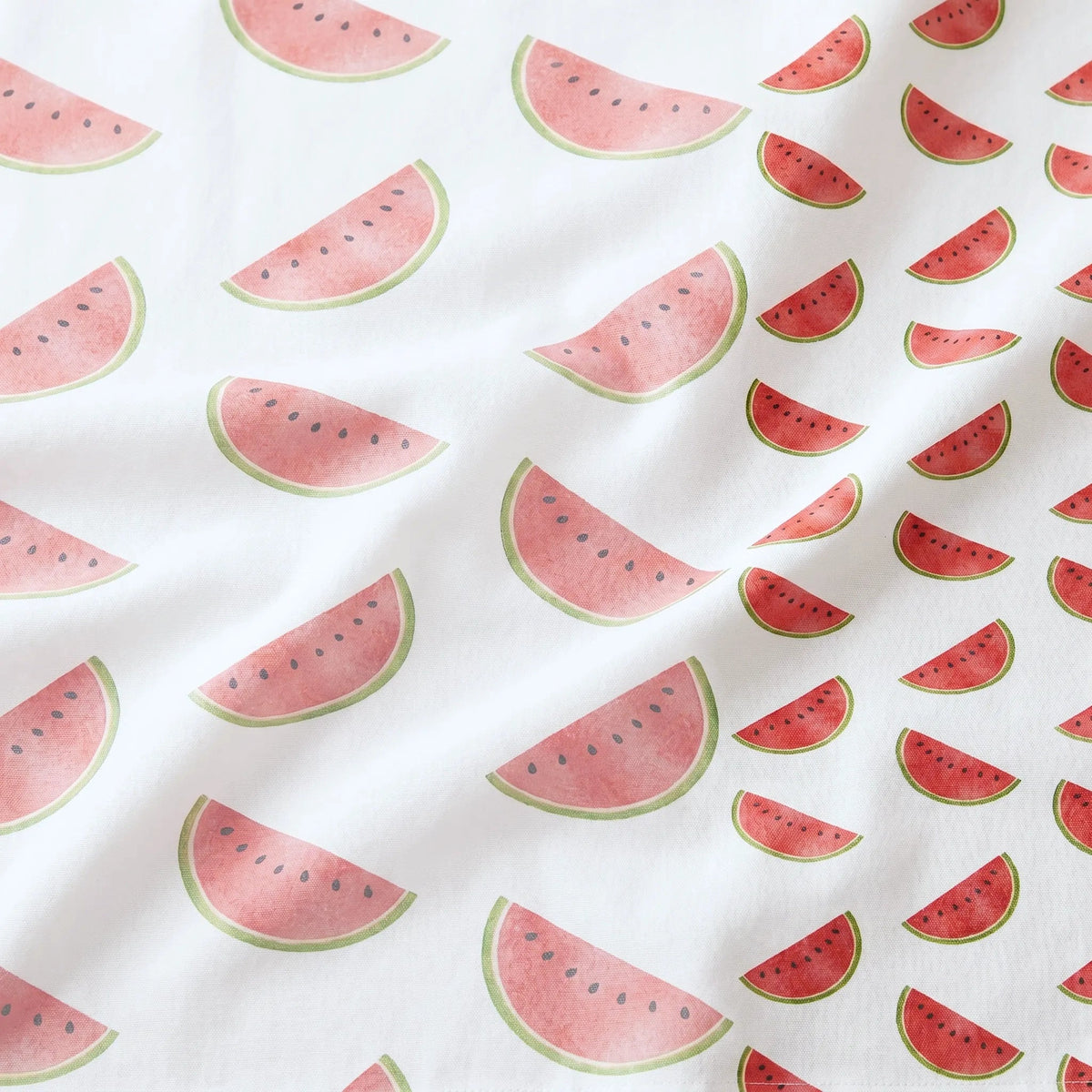 White cotton kitchen towel close up with a repeating watermelon slice pattern in red, pink, and green. from Hem And Tassel