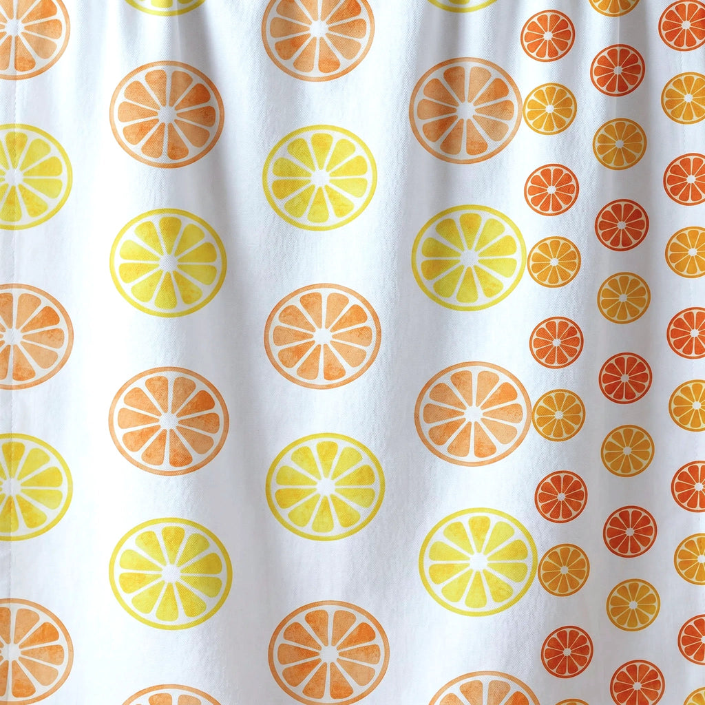White cotton kitchen towel close up with a repeating orange slice pattern in light and dark orange and yellow from Hem And Tassel