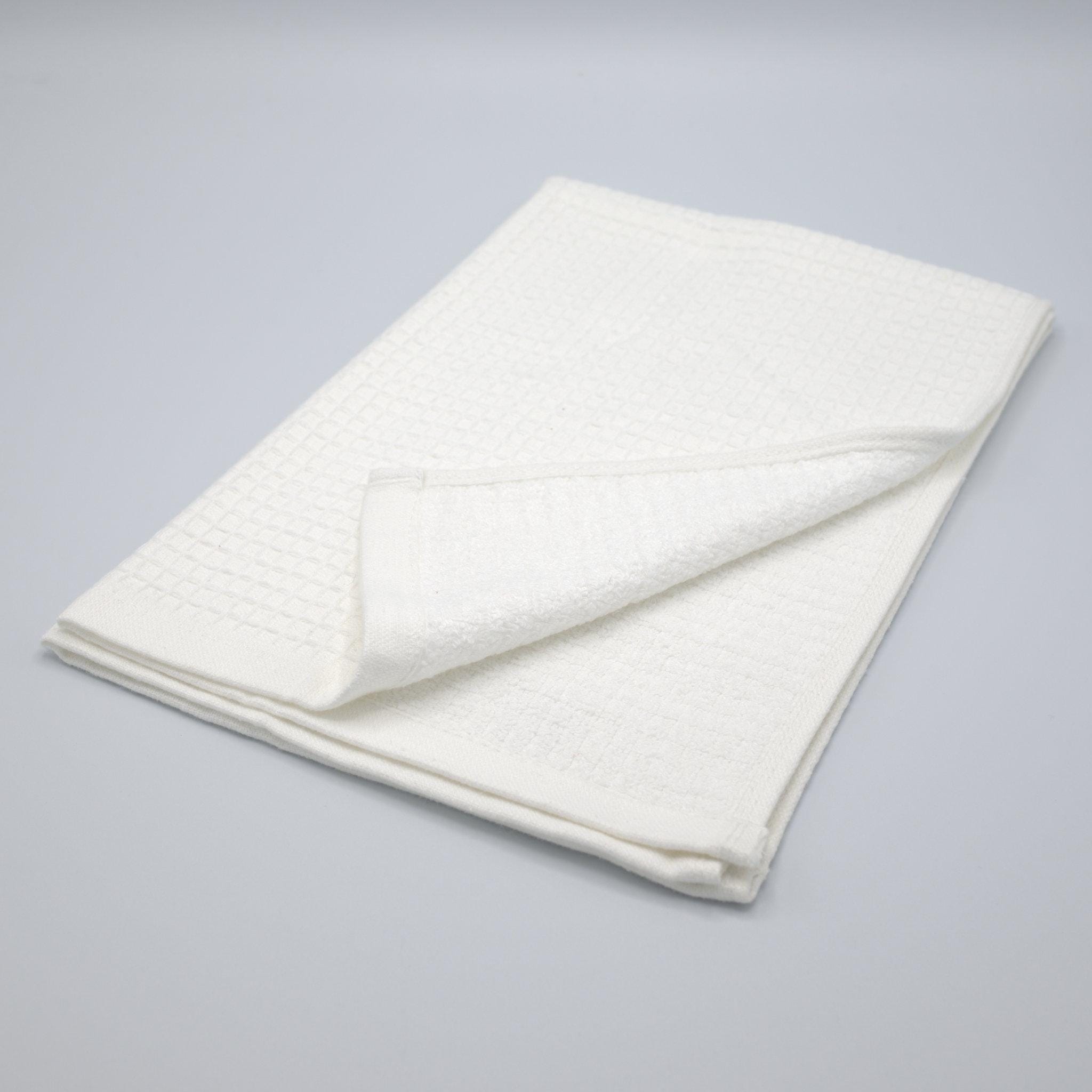 Folded Jekyll and Hyde white towel with waffle texture on one side and Terry on the other side on a gray background