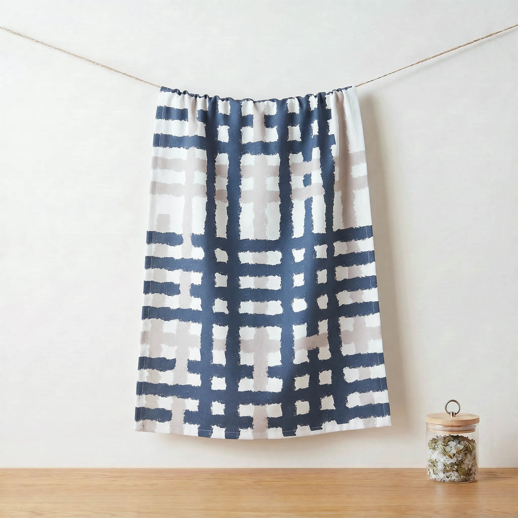 Oil and slate patterned cotton kitchen towel  hanging on a line against a white wall with a wooden floor from Hem And Tassel 