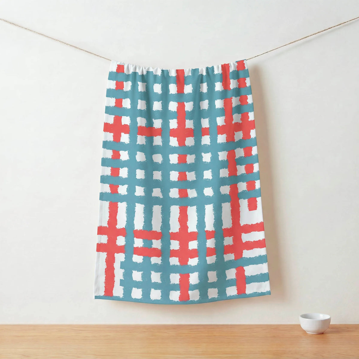 Colorful patterned cotton kitchen towel  hanging on a line against a white wall from Hem And Tassel 