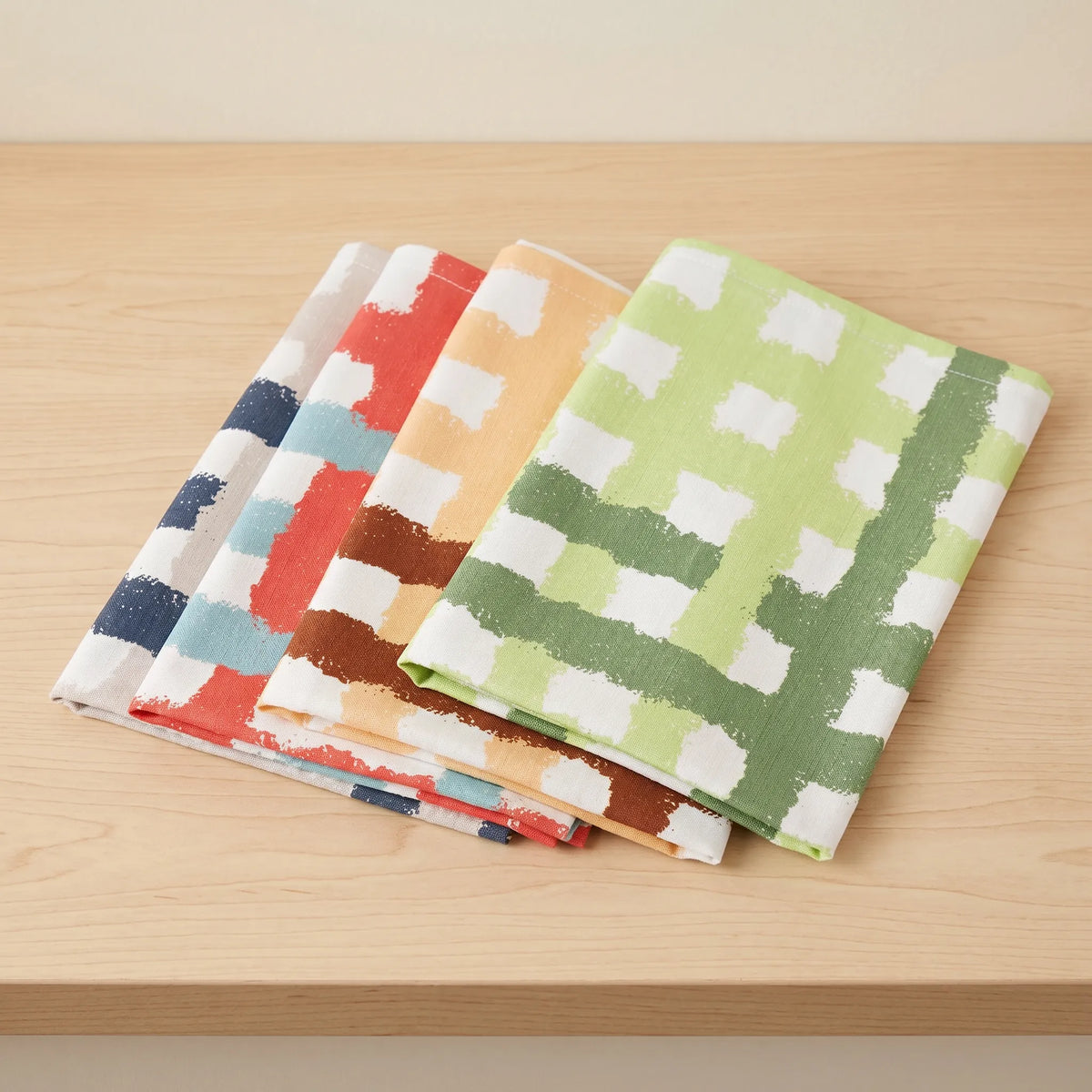 four cotton kitchen towel in colorful checkered pattern on a wooden surface from Hem And Tassel 