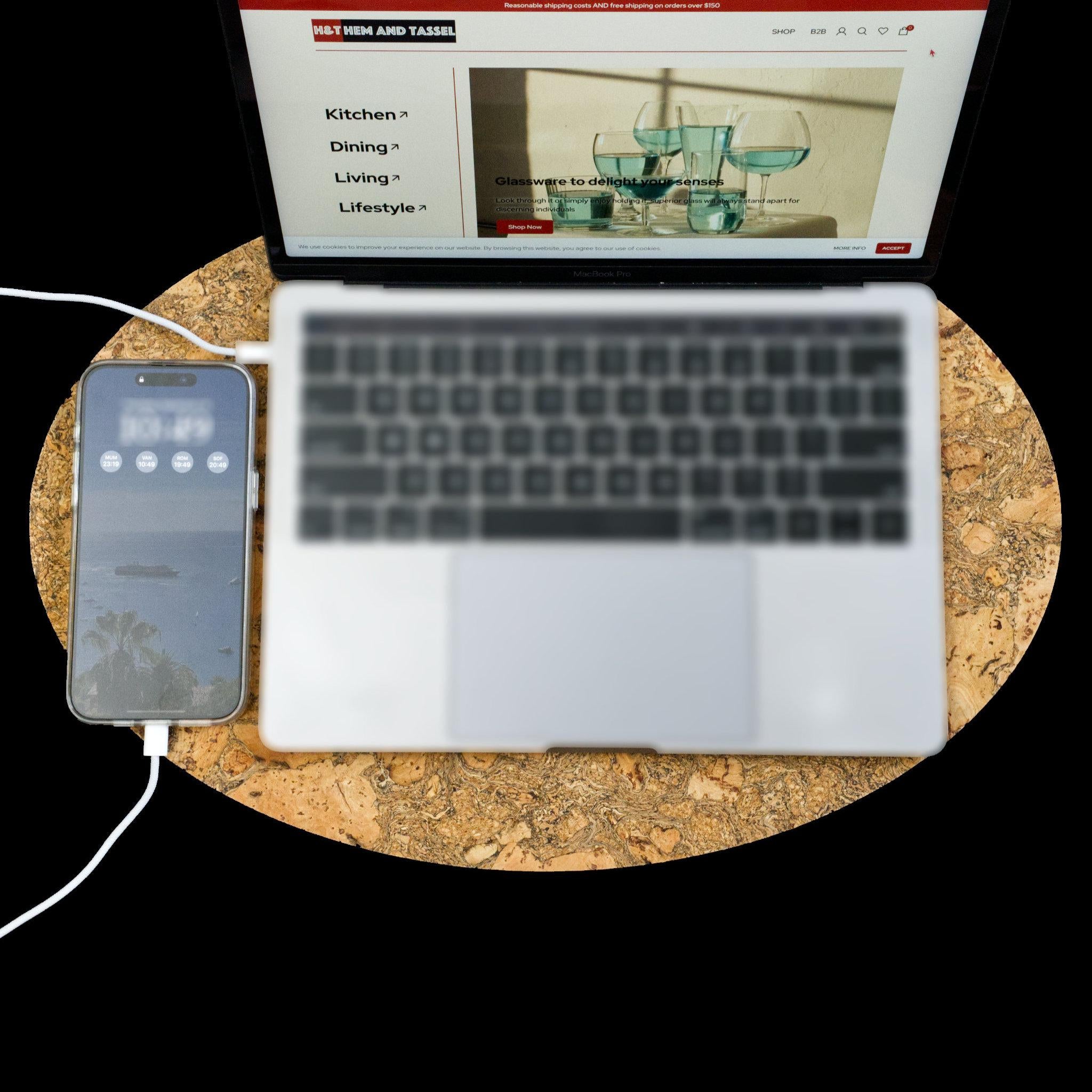 Laptop and smartphone on a large cork placemat with a screen displaying an older version of Hem And Tassel website