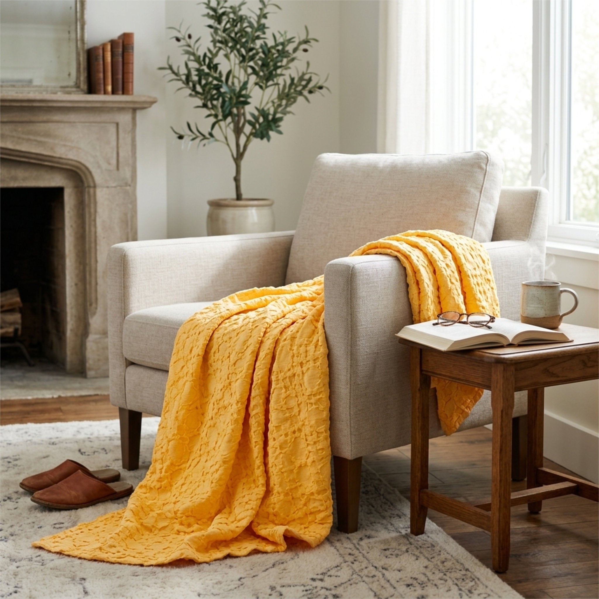 A cozy living room scene featuring a box waffle mild mango colored woven throw blanket hemmed on four sides, draped over a light beige armchair next to a small wooden side table with an open book and a mug.
