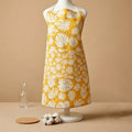 Yellow apron with white floral pattern on a mannequin against a beige background