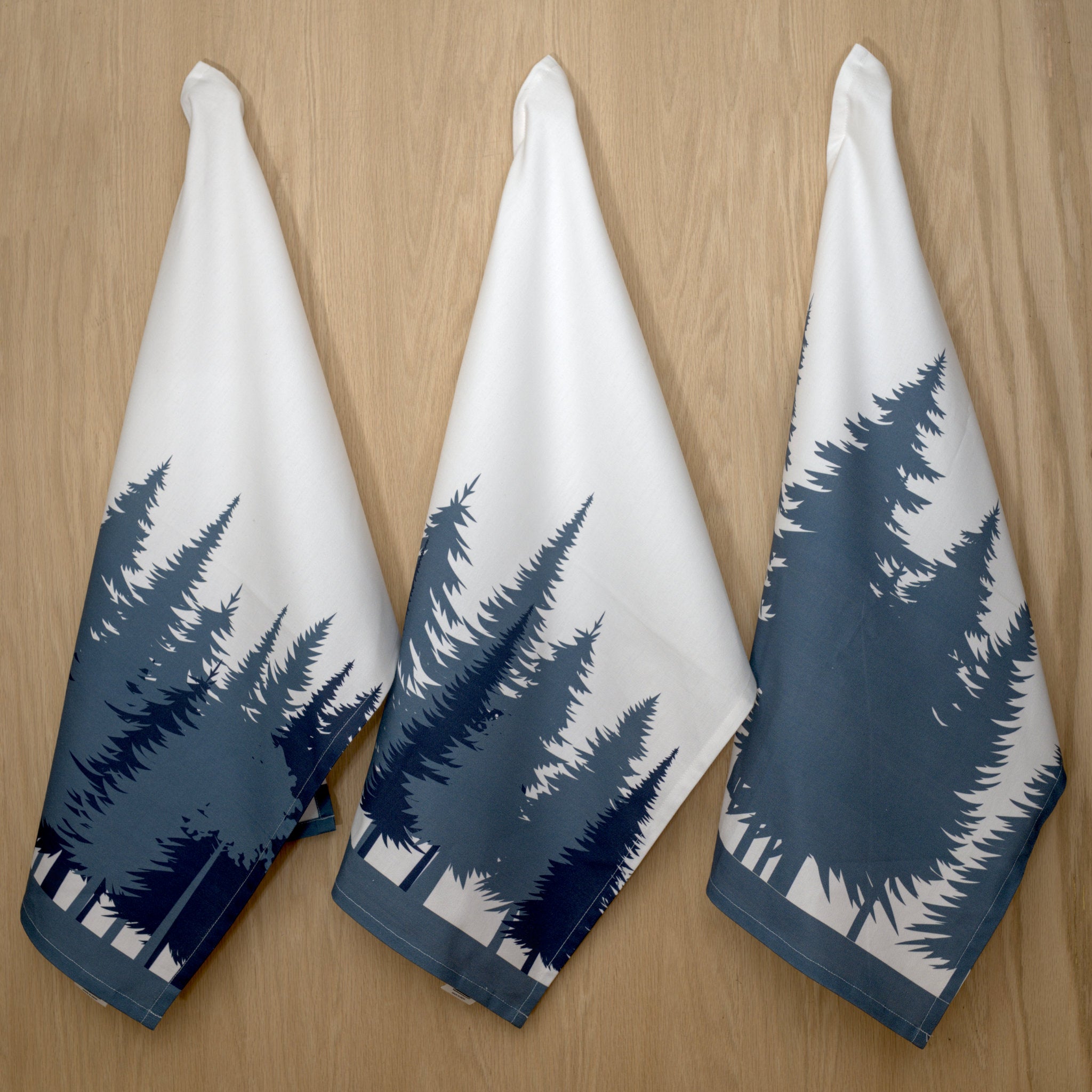 three kitchen towels in rich cotton percale with the park design hanging on a wood background