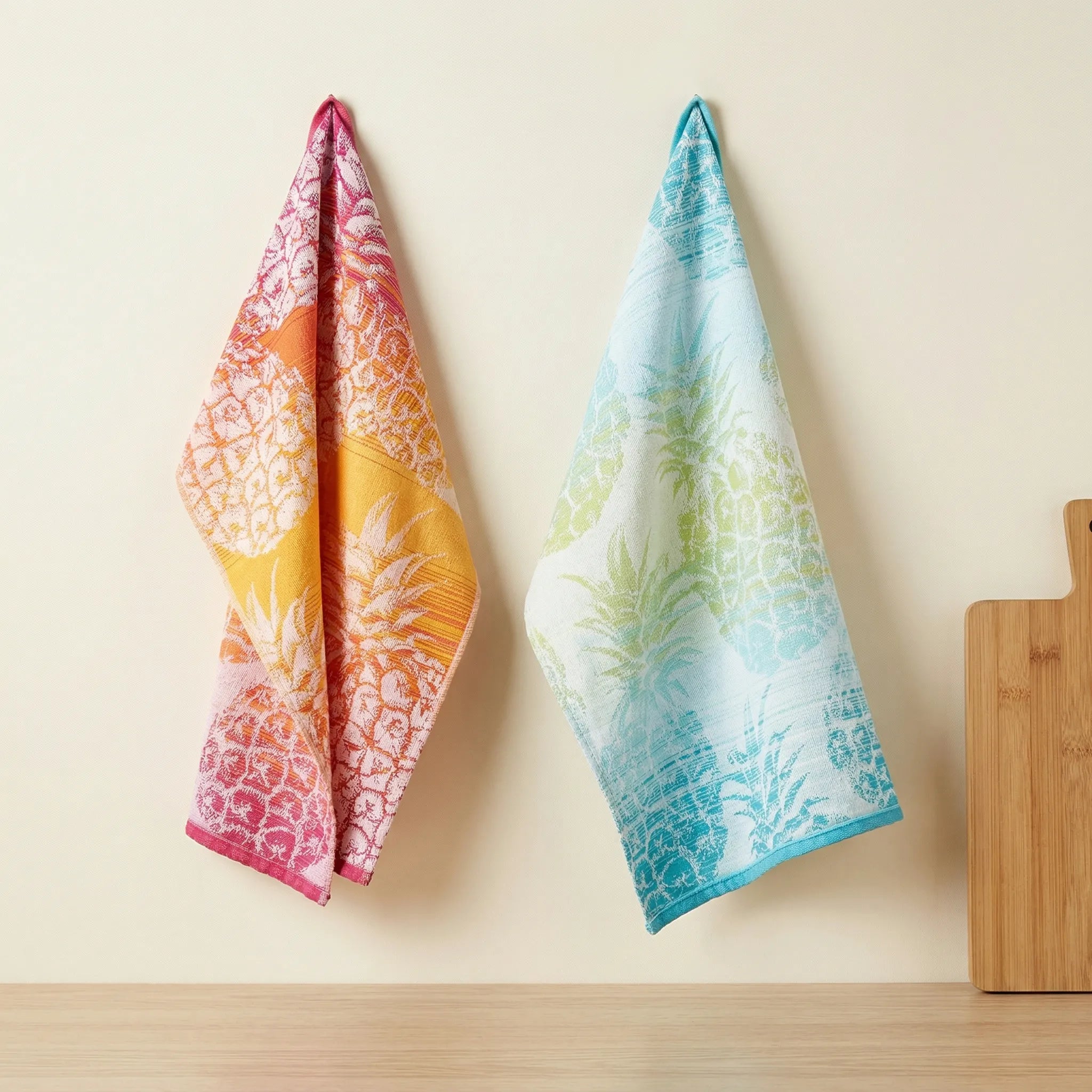 colorful jacquard kitchen towels of 100% cotton - with a pineapple pattern in a set of 2 hanging against a cream colored backdrop from Hem And Tassel 