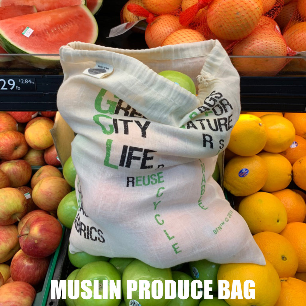 Muslin produce bag with text in a grocery store setting with fruits and vegetables from Hem And Tassel 
