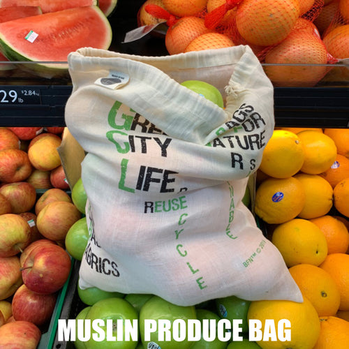 Muslin produce bag with text in a grocery store setting with fruits and vegetables from Hem And Tassel 