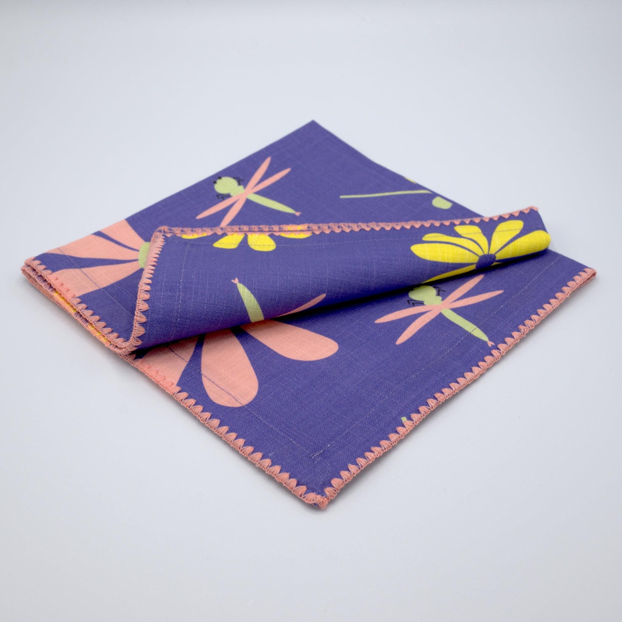 slub-cotton dinner napkin of shy dragonfly design in purple against light grey backdrop- from Hem And Tassel