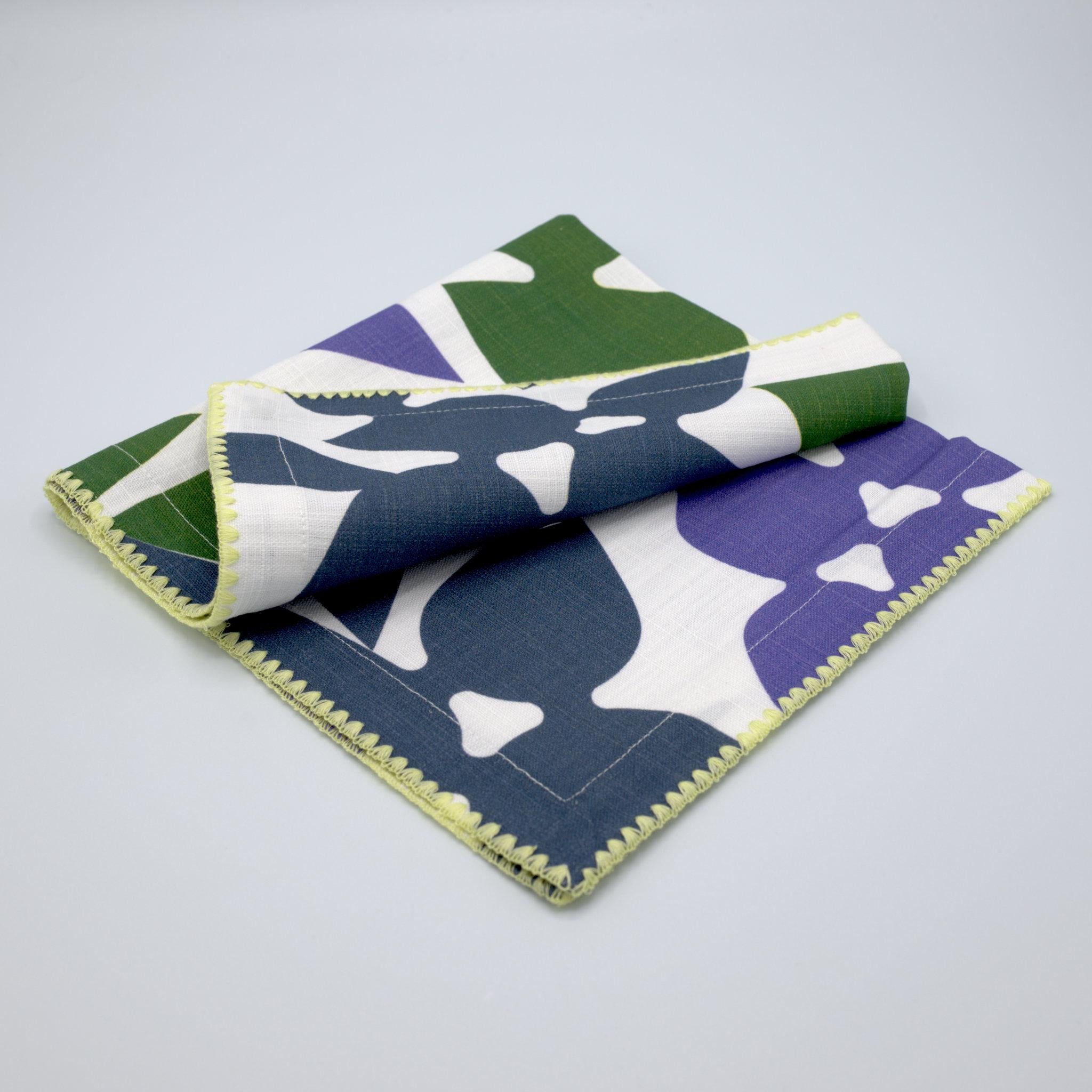 celebration slub cotton dinner napkin of green and purple print on white, against a light grey background - from Hem And Tassel