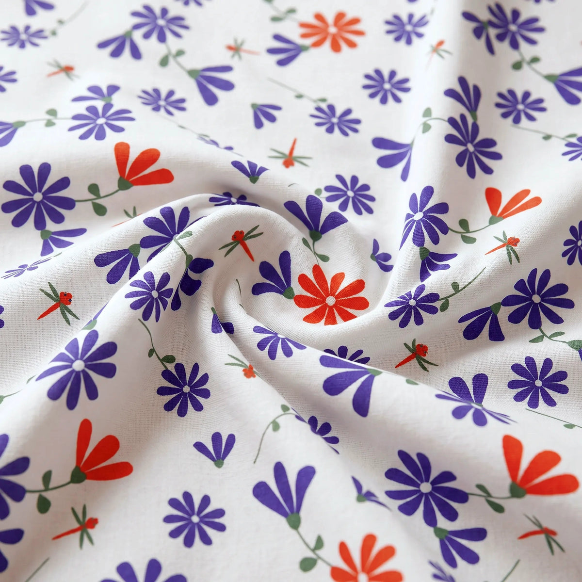 close up of White cotton kitchen towel with a colorful floral print featuring purple and red flowers with green stems, draped in soft folds from Hem And Tassel 