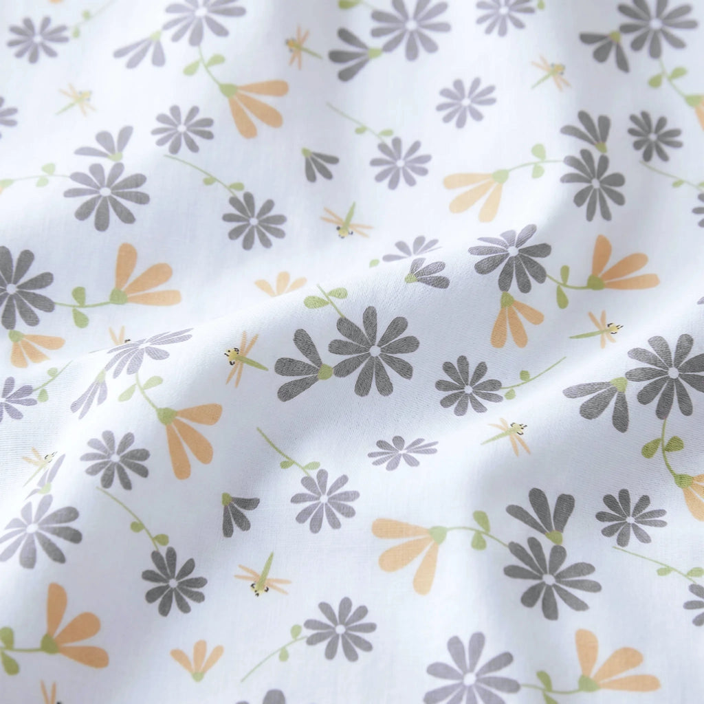 close up of White cotton kitchen towel with a delicate repeating floral and dragonfly print in muted gray, soft orange, and light green from Hem And Tassel 