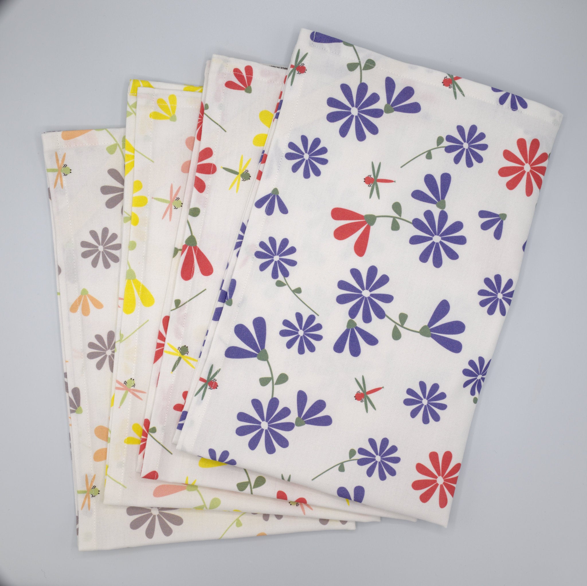 Set of four Shy Dragonfly kitchen towels with floral patterns on a gray background from Hem And Tassel 