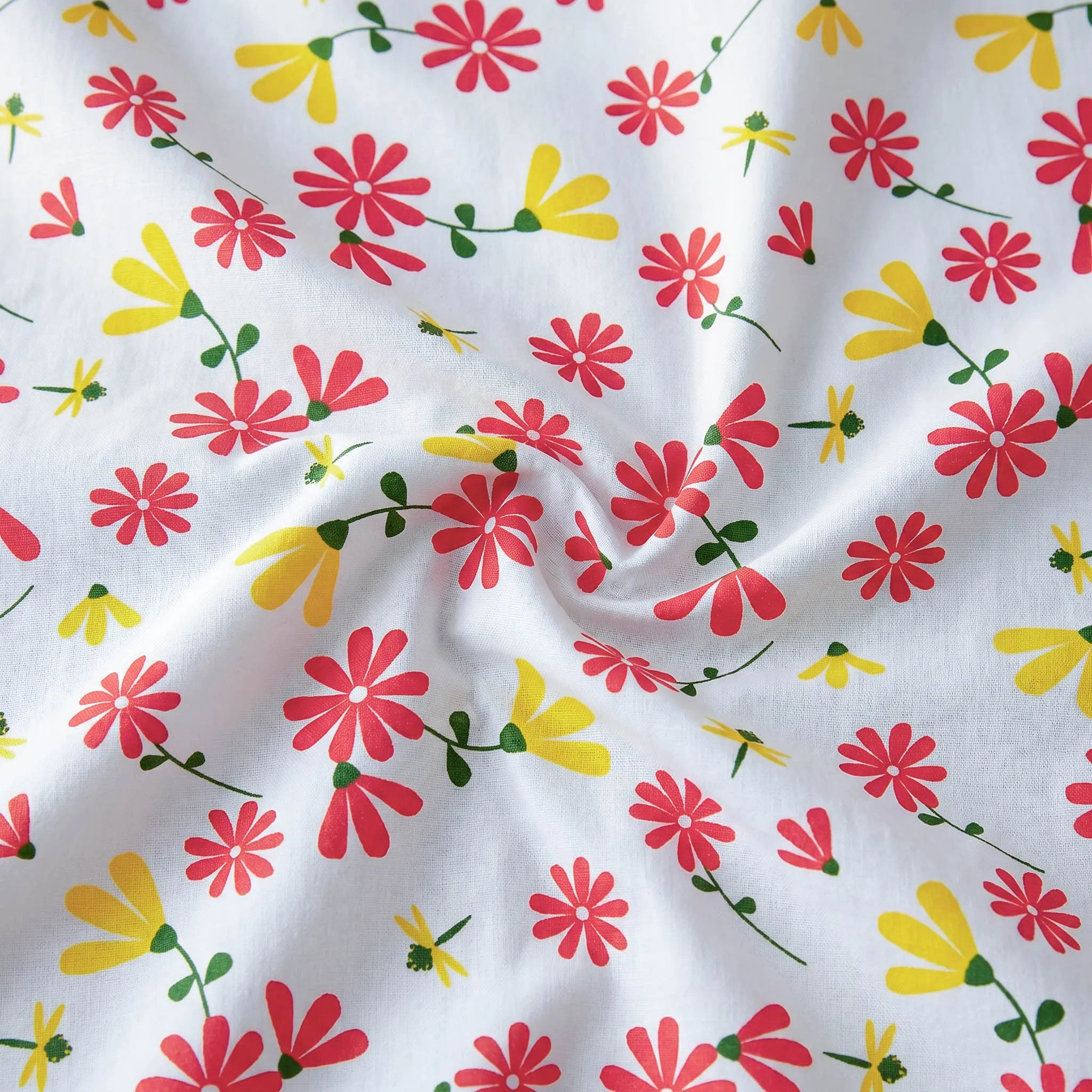 close up of White cotton kitchen towel with a repeating pattern of red and yellow flowers with green stems, shown in a close-up with a central swirl.