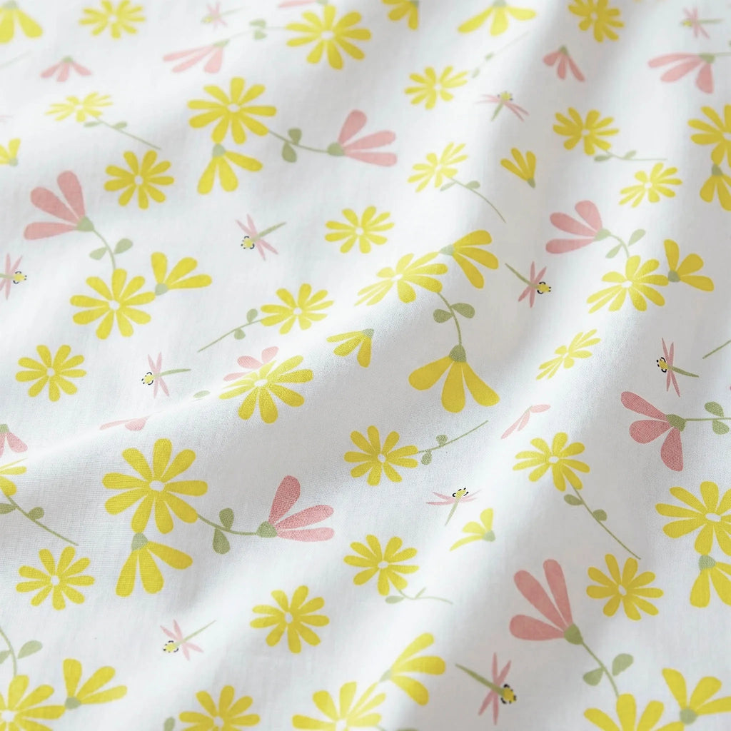 Close up of White cotton kitchen towel with a delicate floral print featuring yellow daisies, pink blossoms, and small green leaves from Hem And Tassel 