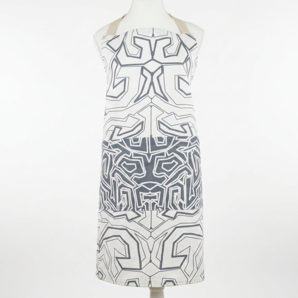 A sleeveless white apron with a oil grey maze-like geometric pattern, displayed on a mannequin torso against a plain white background from Hem And Tassel 