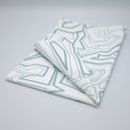 Folded tea towel in rich percale cotton with light blue squiggles geometric patterns on a gray background