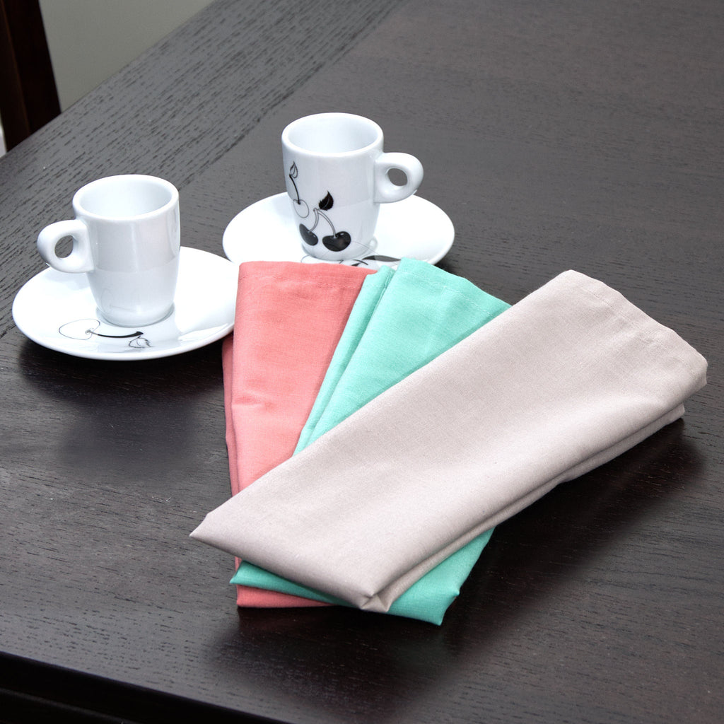 Stack of Three breezy soft dusty pastel colored towels on a dark surface with two white espresso cups.