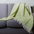 Green patterned reversible cotton throw of garden pattern draped over a gray sofa