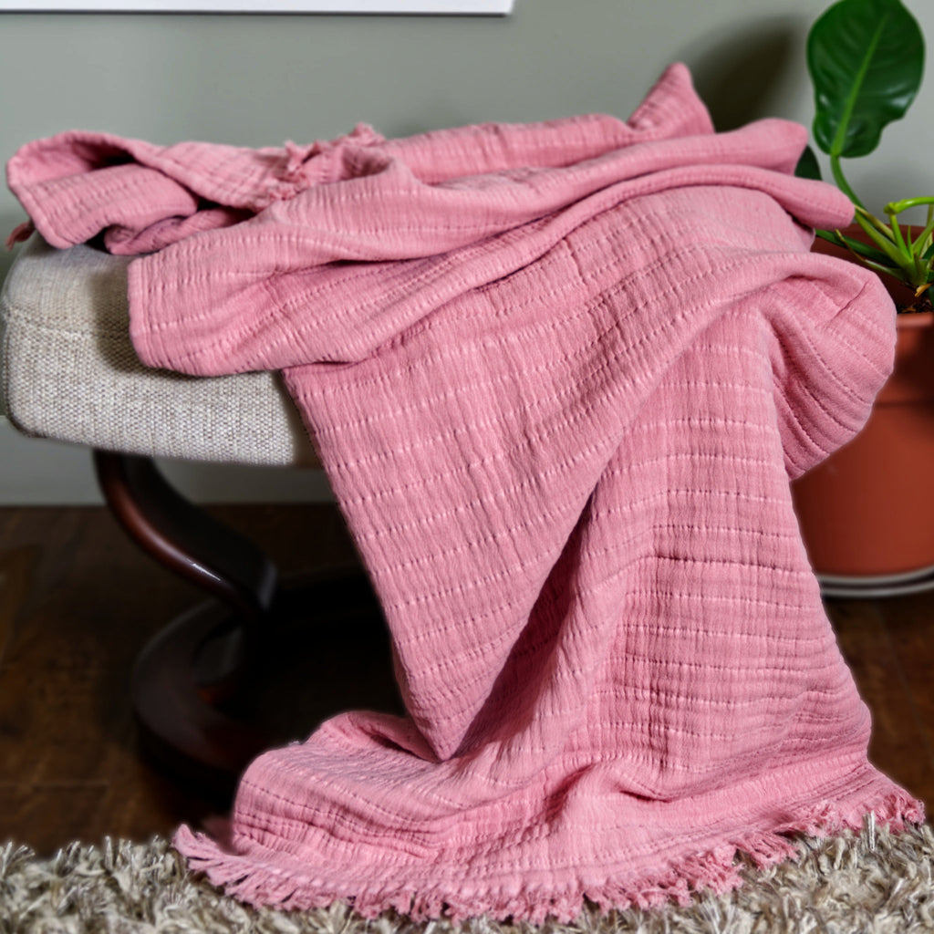 close up of wearable pure cotton seersucker throw in rose pink color on sofa with frills shown hanging from its edge - from Hem And Tassel