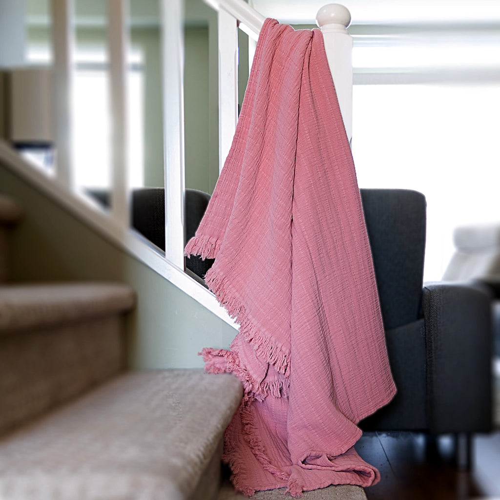 stair baluster draped with wearable pure cotton seersucker throw in rose pink color with living room setting in the back - from Hem And Tassel