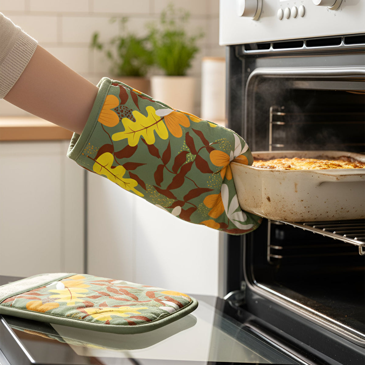 oven mitt and pot holder of the yellow oak style in the Leaves collection, being used to extract a casserole of freshly baked food from the oven from Hem And Tassel