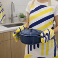 Person holding a blue pot in a kitchen wearing a yellow and navy striped apron and gloves.