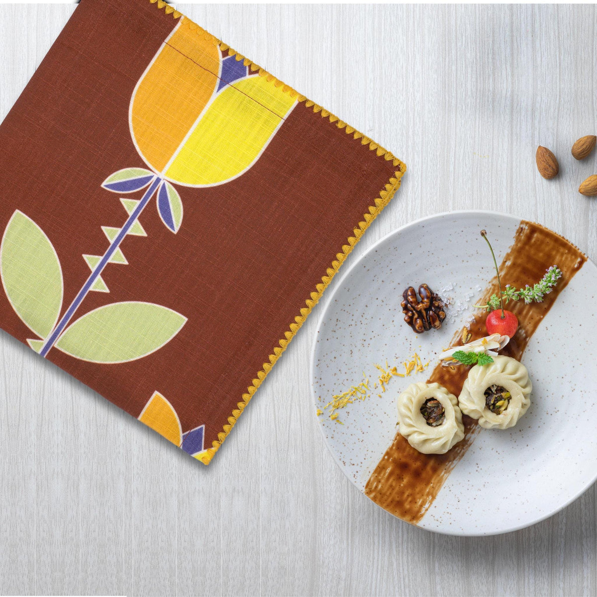 slub-cotton dinner napkin of Lip Tulip design in clay, with a plate of dessert - from Hem And Tassel