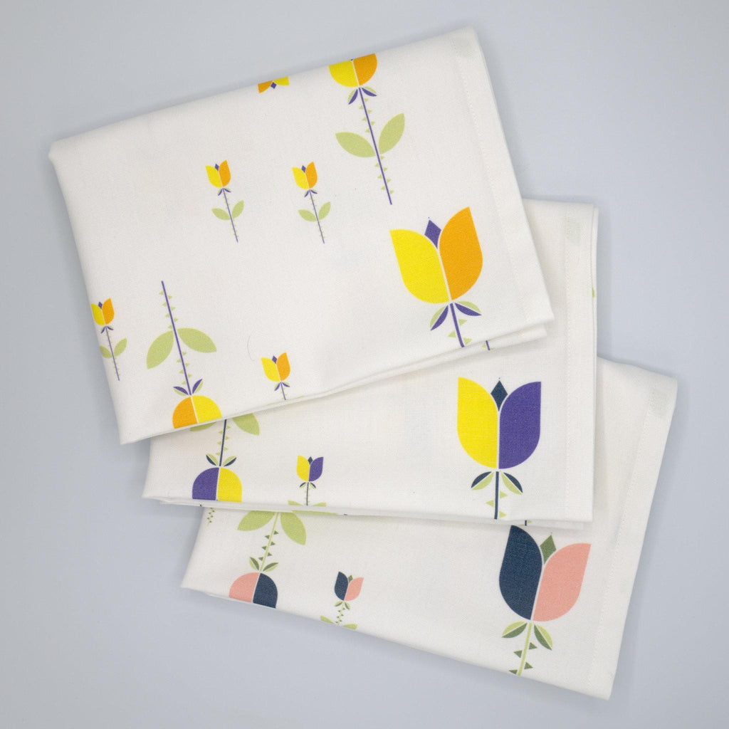 Set of three art deco lip tulip folded towels with colorful floral patterns on a gray background from Hem And Tassel 