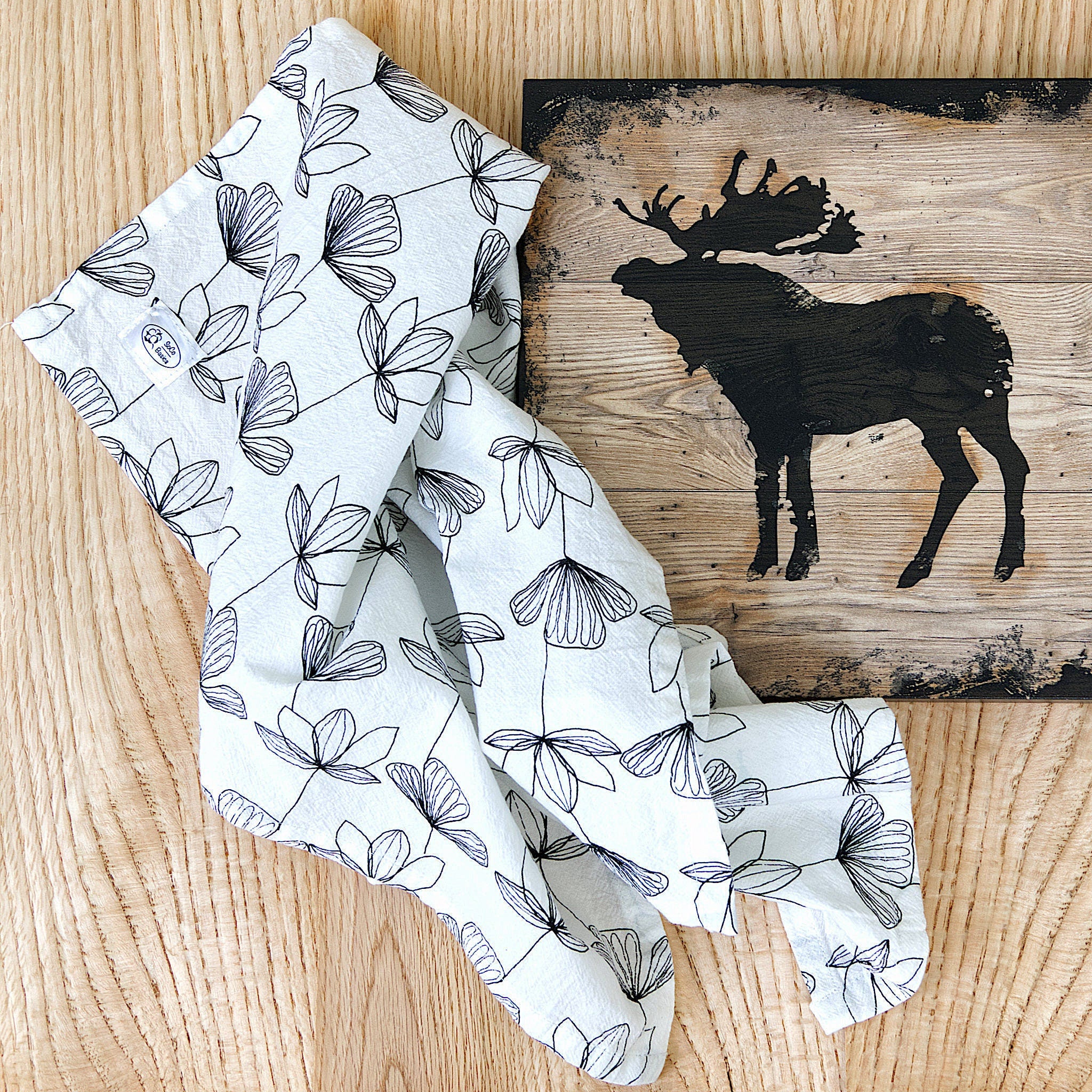 stems flour sack towel with reindeer decor from Hem And Tassel on wood background
