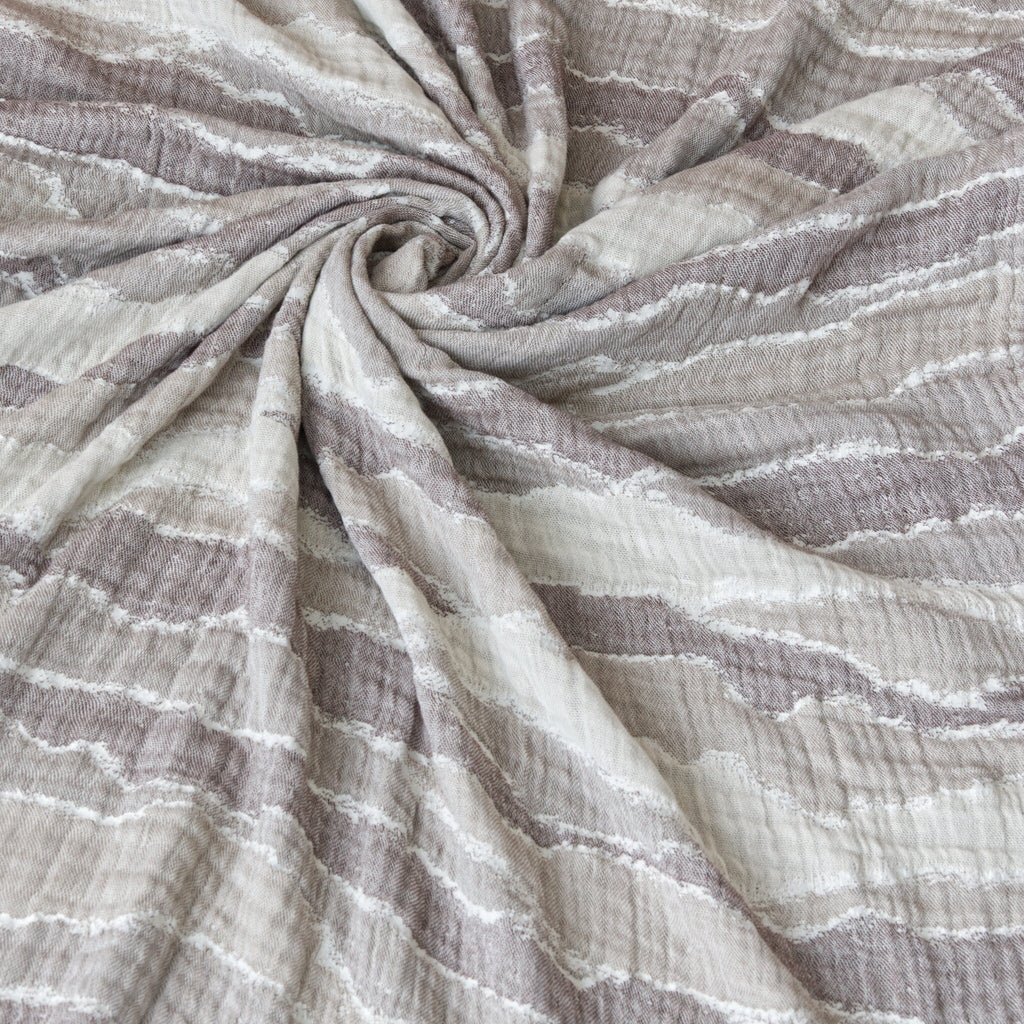 Close-up of textured fine seersucker guaze fabric of the throw blanket with a swirling pattern