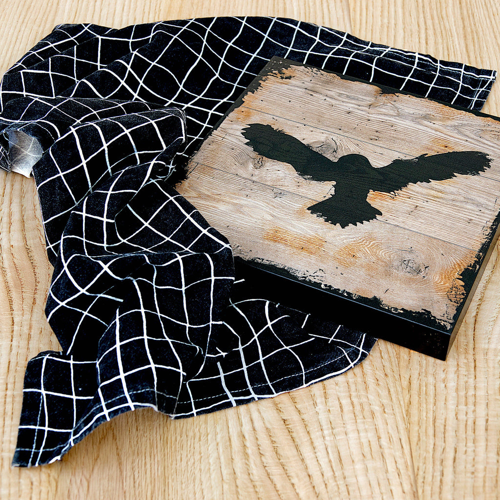 black floursack towel in strings pattern with eagle decoration on wood background from Hem And Tassel 