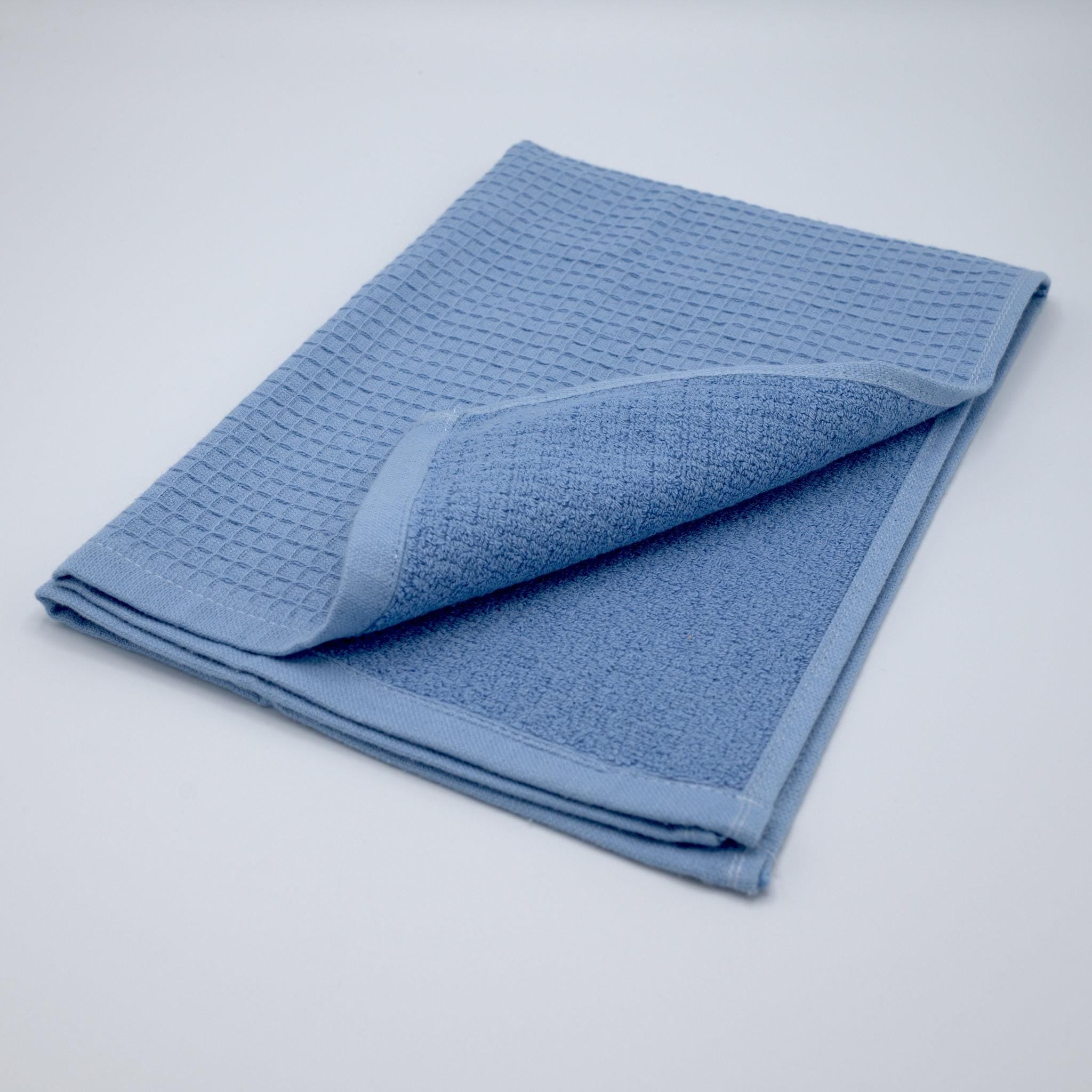 Folded blue Jekyll and Hyde kitchen towel on a gray background flipped open to see both surface of the towel