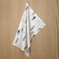 rich cotton percale kitchen towel of cloud and cactus design hanging against a wooden backdrop - from Hem And Tassel