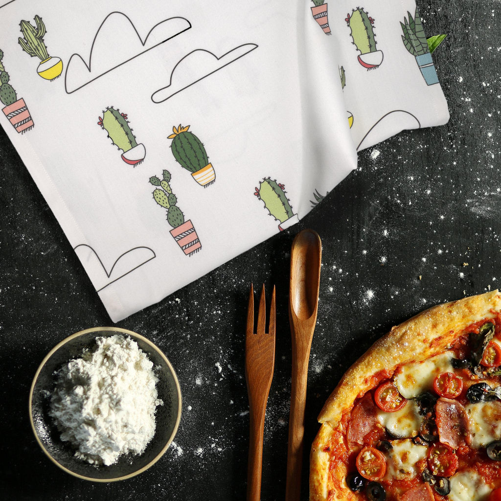 Towels with cactus and clouds pattern, pizza, and utensils on a dark surface from hem and tassel