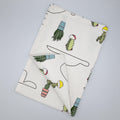 Folded tea towel with cactus and clouds pattern on a light gray background from hem and tassel